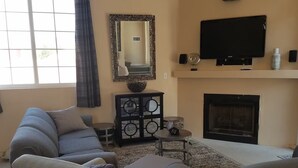 Ein Wohnzimmer mit Ecksofa, Kamin, Fernseher und einem dekorativen Spiegel.