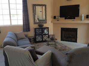 A living room with a sectional sofa, a fireplace, a television, and a decorative mirror.