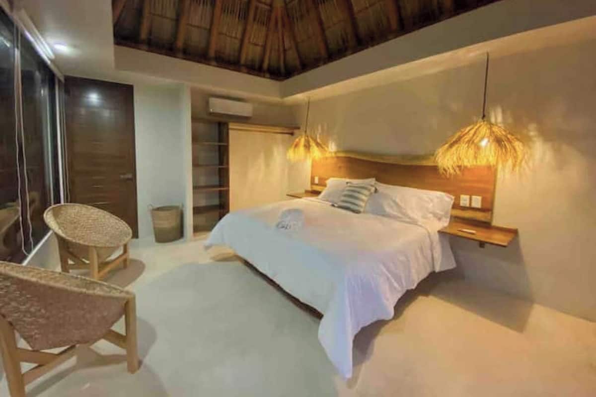 A bedroom with a bed, a chair, a nightstand, and a ceiling fan.