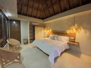 Una camera da letto con un letto, una sedia, un comodino e una ventola a soffitto.