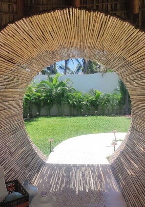 A circular bamboo structure with a view of a green lawn and palm trees. - Boutique Hotel Al Dea (Acapulco de Juárez)