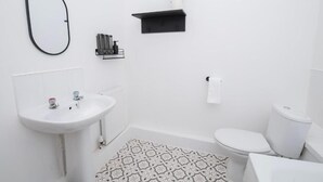 A bathroom with a white sink, toilet, and a patterned rug. - Amber Serviced Accommodation Rooms (Hull)