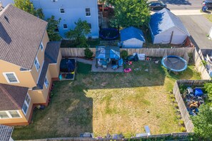 A residential backyard with a trampoline, a covered patio, and a fenced play area. - Plainfield Retreat Near NYC-Travel Nurse Friendly (Plainfield)