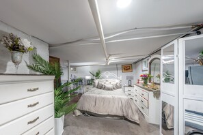 Ein Schlafzimmer mit Bett, Kommode, Nachttischen und einem Spiegel.