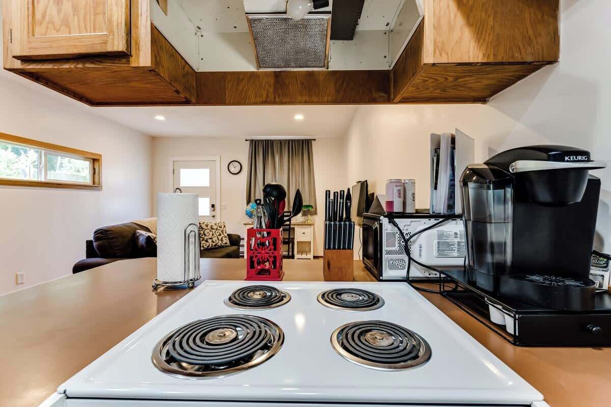 A modern kitchen with a white stove, a coffee maker, and a red appliance.