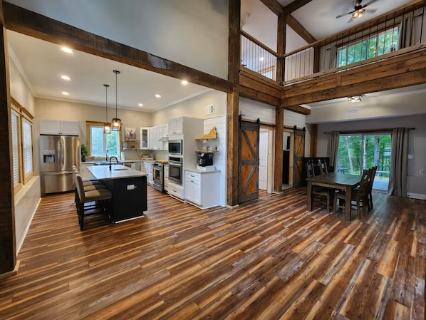 A spacious kitchen with wooden floors, a dining area, and a loft with a balcony.