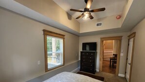 Quarto com cama, penteadeira, ventoinha no teto e janela.