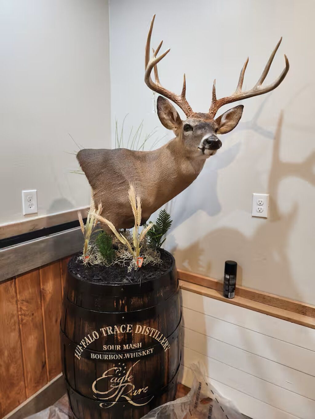 Et gevir monteret på en tønde med et skilt, der viser 'Buffalo Trace Distillery Bourbon Whiskey'.