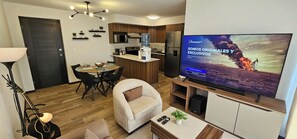 A modern living room with a TV, sofa, dining table, and kitchen area. - Charming 2-bedroom apartment in Carretera a el Salvador near Casa de Dios. (Ciudad de Guatemala)