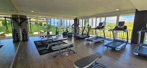 A spacious gym with various exercise equipment, large windows, and a view of greenery. - Charming 2-bedroom apartment in Carretera a el Salvador near Casa de Dios. (Ciudad de Guatemala)