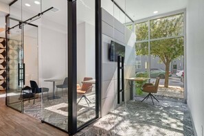 A modern office space with glass walls, a flat-screen TV, and a view of the street outside. - Cozy 1-bedroom apartment in charming Plano (Plano)