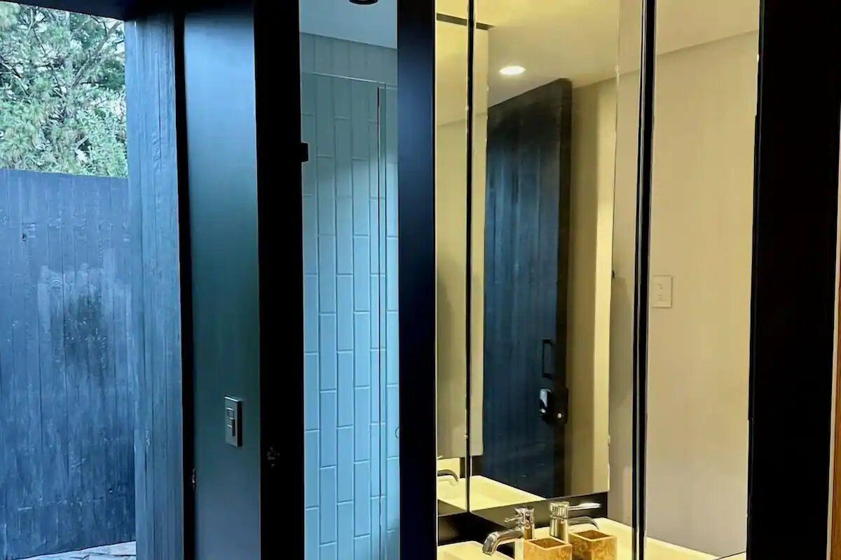 Un baño moderno con mampara de vidrio, lavabo y espejo.