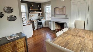 A spacious kitchen with a dining table, white cabinets, and a fireplace. - Historic DT Building, Walk to Shops & Dining (Lynchburg)