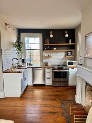 A kitchen with white cabinets, a dishwasher, an oven, and a microwave.