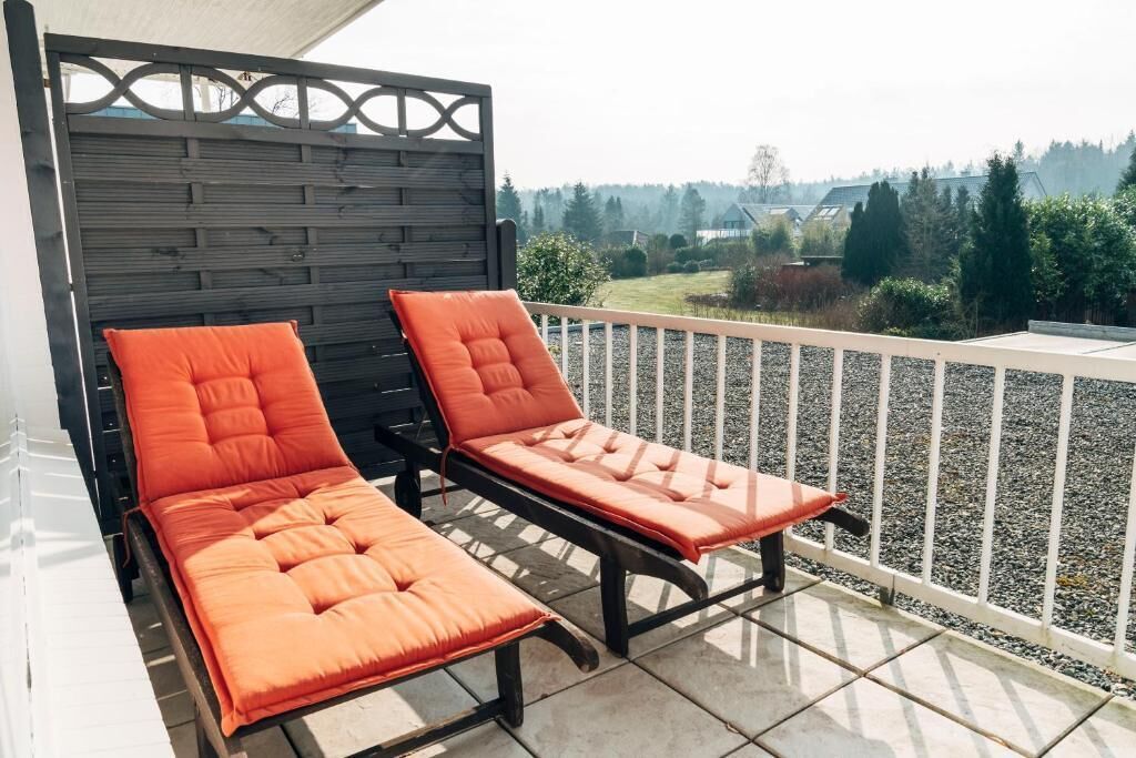 Ein Balkon mit zwei Liegestühlen und einer Zierwand.