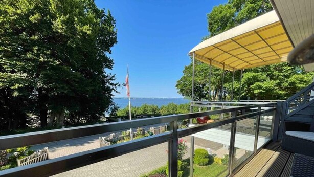 Un balcon donnant sur un espace paysager aménagé et surmonté d’un mât pour drapeau.