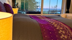 Une chambre d’hôtel dotée d’une grande fenêtre, d’un lit recouvert d’une courtepointe, et offrant une vue sur l’extérieur.