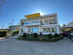 Ein modernes, zweistöckiges Gebäude mit Balkon, einer Flagge und einem gepflasterten Zugangsweg.