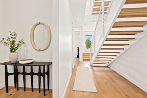 A modern interior with a staircase, a round mirror, and a table with a vase. - Spectrum - Garage - 0.5 mi DT (Bentonville)
