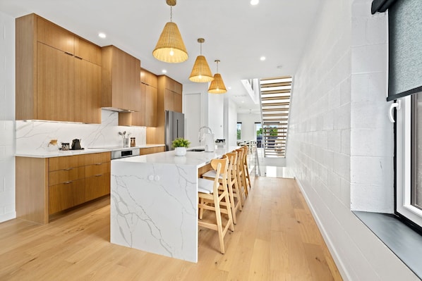 A modern kitchen with wooden cabinets, a marble island, and pendant lighting. - Spectrum - Garage - 0.5 mi DT (Bentonville)