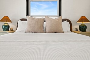 A hotel room with a large bed, two nightstands, lamps, and a view of the sky through a window. - Spectrum - Garage - 0.5 mi DT (Bentonville)