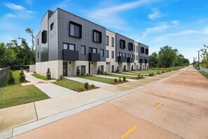 A modern multi-story building with a flat roof, large windows, and a clean, landscaped driveway. - Spectrum - Garage - 0.5 mi DT (Bentonville)