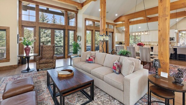 A spacious living area with a large sofa, a coffee table, and a fireplace. There are large windows and a view of the outdoors. - BRAND NEW - Luxury Beaver Creek Mountain Retreat - Sleeps 16 (Edwards)