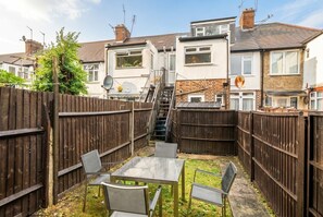 Ein Garten mit Tisch und Stühlen, einem Holzzaun und einer Treppe, die zu einem Haus führt.