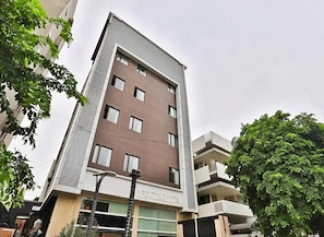 A multi-story hotel with a modern architectural design, featuring a prominent entrance, balconies, and a sign indicating it is a hotel. - Deluxe Hotel Navjivan (Ahmedabad)