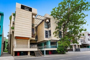 Un edificio de varios pisos con fachada plana, una escalera visible y un letrero que indica que es un complejo de apartamentos con servicios.