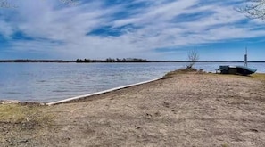 A lakeside view with a boat dock, a picnic table, and a grassy area.