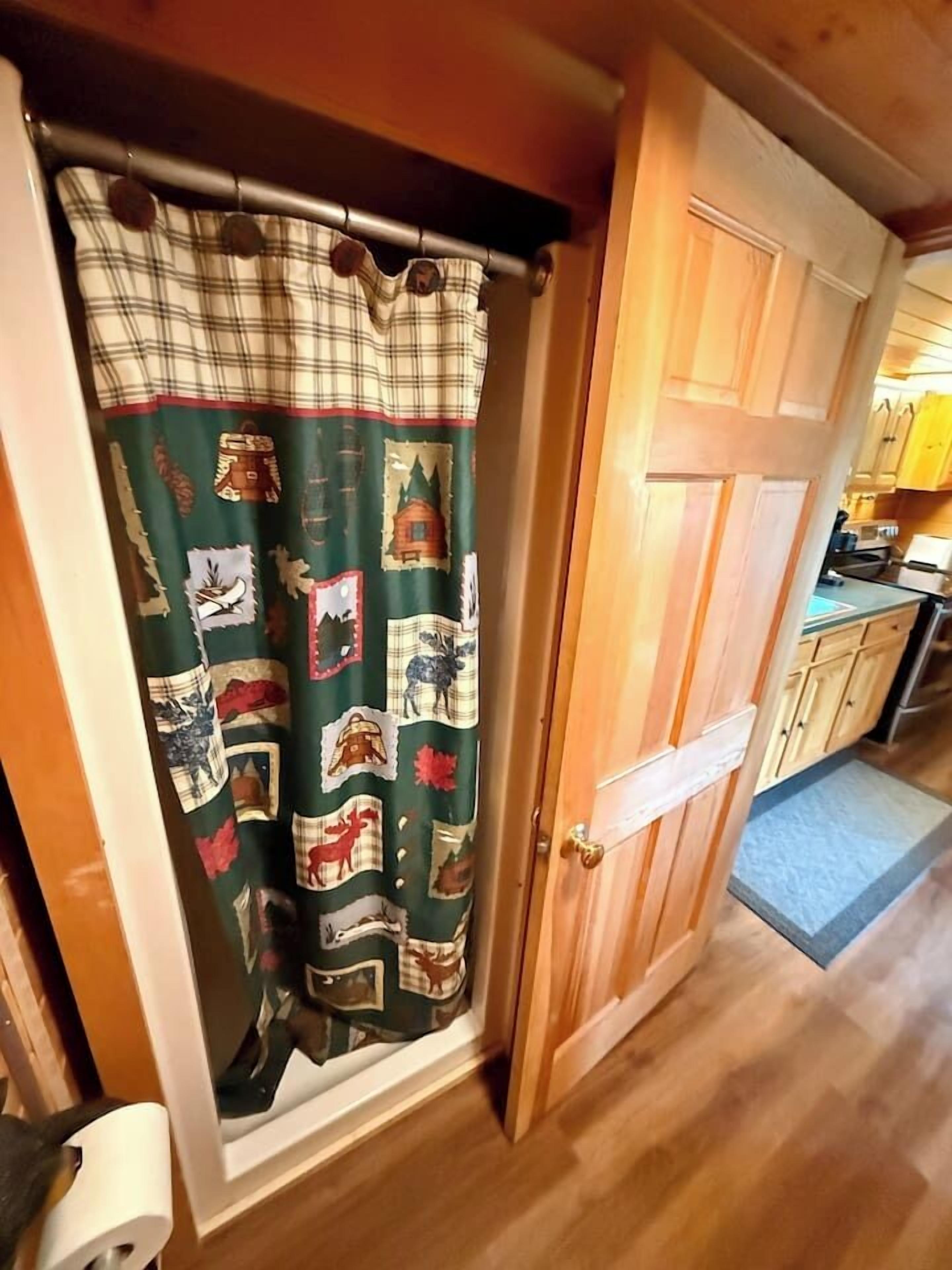 A wooden door with a metal handle, a green curtain with various patterns, and a wooden floor.