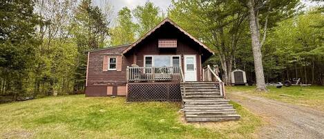A cabin with a front porch, a small deck, and a staircase leading to the entrance.