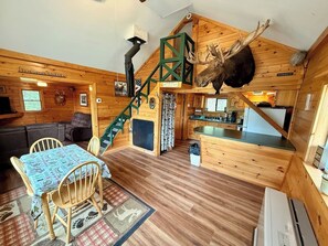 A cabin interior with a dining area, kitchen, and a staircase. - Camp Up North | Water Access | Snowmobile & ATV (Rockwood)