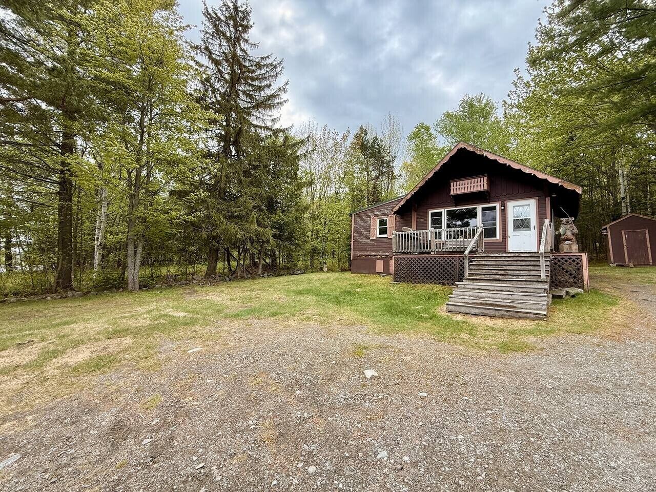 Eine Holzhütte mit Veranda, Treppe und umzäuntem Garten.