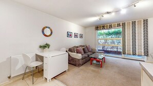 En moderne stue med en hvid radiator, en brun sofa, et glasbord og et hvidt skrivebord med stol.