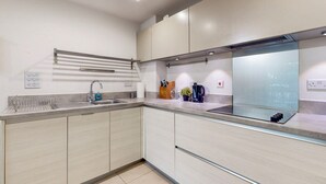 Et moderne køkken med vask i rustfrit stål, indbygget ovn og en glasbagplade.