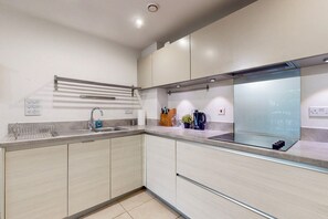 Eine moderne Küche mit Spüle aus Edelstahl, einem eingebauten Backofen und einer Glasrückwand.