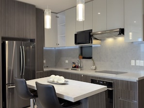 Uma cozinha moderna com eletrodomésticos de aço inoxidável, uma ilha central e iluminação pendente.