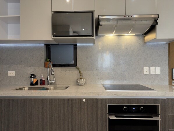 A modern kitchen with a built-in oven, a microwave, and a stainless steel range hood.