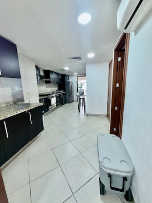 A kitchen with dark cabinets, a countertop, and a white tiled floor. - Luxury 3-Bedroom Apartment with Panoramic Ocean Views at the Grand Venetian (Puerto Vallarta)