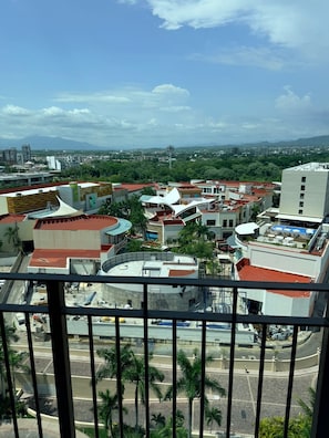 A cityscape with modern buildings, a prominent round structure, and a distant mountain range. - Luxury 3BR & Panoramic Ocean View Grand Venetian (Puerto Vallarta)