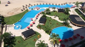 Oversigtsbillede af et resort med flere swimmingpools, en strand og en velholdt græsplæne.