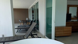 Un espace de vie extérieur moderne comprenant un jacuzzi, une table à manger avec des chaises et une porte-fenêtre coulissante donnant accès à une chambre.