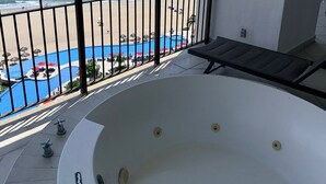 Un balcon avec vue sur la plage et un jacuzzi.