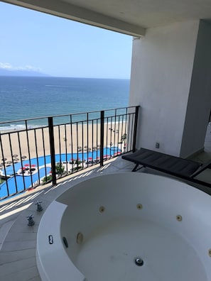 Ein Balkon mit Blick auf den Strand und einer Whirlpool.