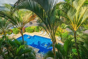 A swimming pool surrounded by palm trees and lounge chairs. - "Oceanfront" Welcome to your ocean view oasis! Steps to beach + Private balcony  (Kapaʻa)