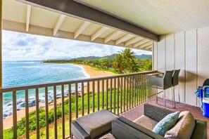 A balcony with a view of a beach and ocean, a sofa, and a TV. - "Oceanfront" Welcome to your ocean view oasis! Steps to beach + Private balcony  (Kapaʻa)