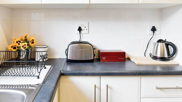 Eine Küche mit weißen Schränken, einem Toaster, einem Wasserkocher und einem Schneidebrett.