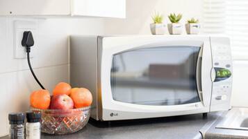 Een keuken met een magnetron, een schaal fruit en een stopcontact.